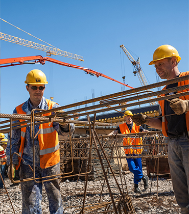 Mannen met helm op en veiligheidshestje aan, aan het werk op de bouw