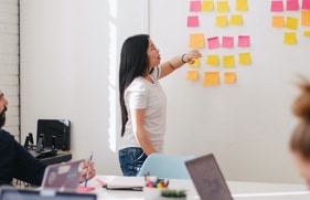 Een vrouw voor een whiteboard met post-its