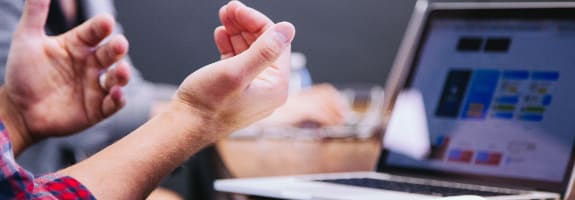 Mensen in discussie met opgeheven handen voor een laptop
