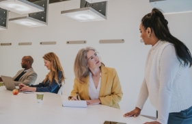 4 collega's zitten in een vergaderruimte en zijn in gesprek met elkaar.