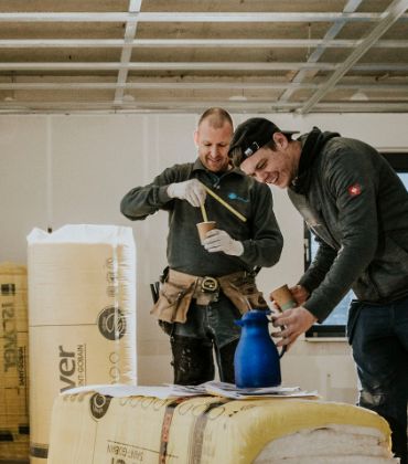 2 jonge mannen lachen en drinken koffie op de bouw.