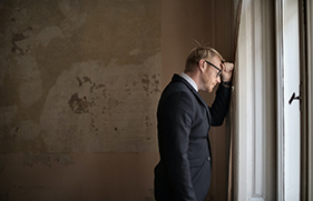 Een ondernemer die met zijn voorhoofd tegen een muur staat en aan het nadenken is