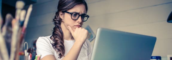 Vrouw die fronsend naar haar laptopscherm kijkt