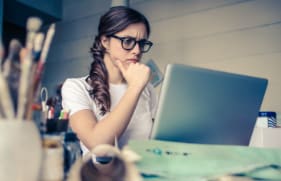Vrouw die fronsend naar haar laptopscherm kijkt