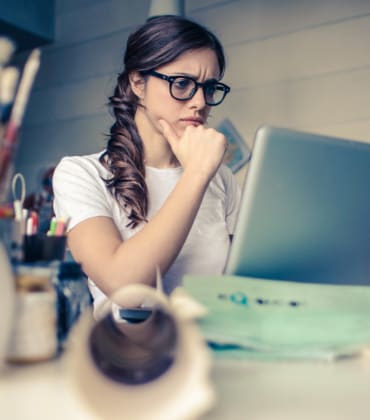 Vrouw die fronsend naar haar laptopscherm kijkt