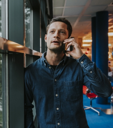 Man staat bij het raam en is aan het bellen