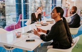 Collega's op kantoor praten met elkaar. Ziekteverzuim is dit jaar met 50% gestegen. 