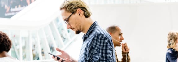 Man kijkt naar de mobiele telefoon in zijn hand