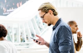 Man kijkt naar de mobiele telefoon in zijn hand