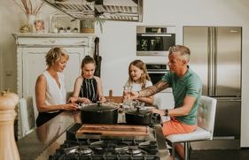Een gezin zit in de keuken aan tafel bij het fornuis te eten