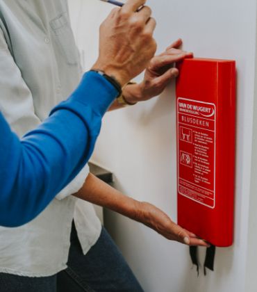 2 mensen hangen een brandblusdeken op.