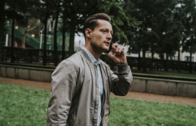 Een man staat met een telefoon aan zijn oor in een park