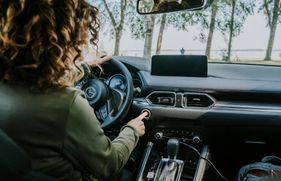 Vrouw zit in auto en start de auto