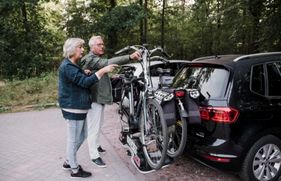 Man en vrouw zetten 2 fietsen op de auto om op fietsvakantie te gaan.