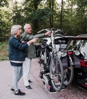 Man en vrouw zetten 2 fietsen op de auto om op fietsvakantie te gaan.