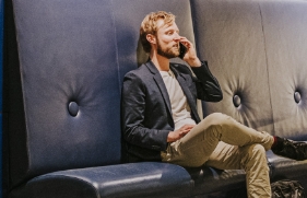 Een man zit bellend op een bankje