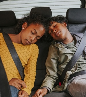 2 kinderen zitten slapend op de achterbank van een auto