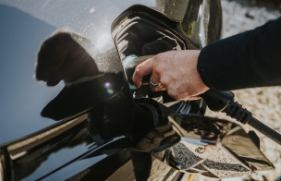 Iemand steekt de stekker in een elektrische auto om deze op te laden