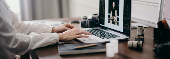 Iemand die thuis achter zijn bureau op een laptop aan het werken is