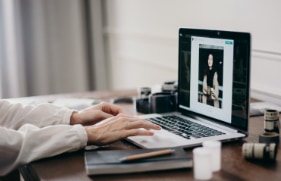 Iemand die thuis achter zijn bureau op een laptop aan het werken is