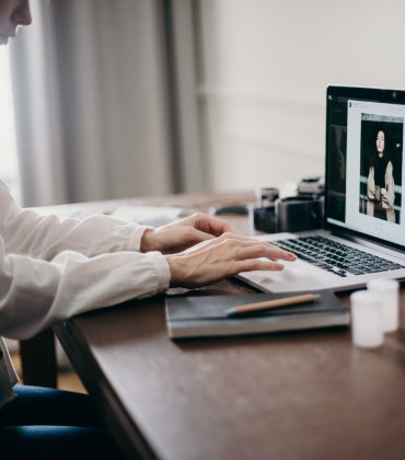 Iemand die thuis achter zijn bureau op een laptop aan het werken is