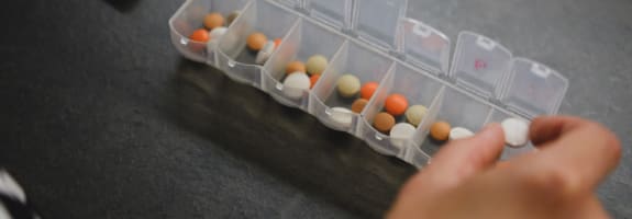 Iemand die een pillendoos vult met medicijnen om mee op reis te nemen