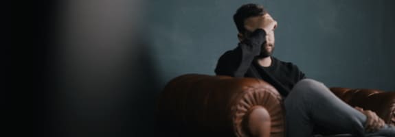 Man in een fauteuil met zijn hand op zijn voorhoofd
