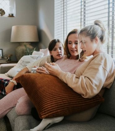 Moeder zit met haar dochters achter de laptop. Waar moet je op letten als je zorgverzekeringen gaat vergelijken?