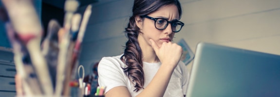 Een vrouw die achter haar laptop zit en met haar ogen fronst