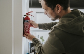 Man hangt brandblusser aan de muur