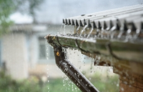 Een dakgoot overstroomt door de grote hoeveelheid regenwater die er vanaf het dak in terechtkomt.