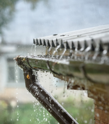 Een dakgoot overstroomt door de grote hoeveelheid regenwater die er vanaf het dak in terechtkomt.