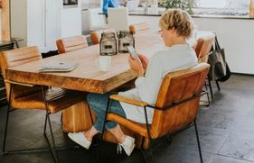 Vrouw zit aan tafel met de telefoon in de hand
