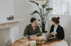 Man en vrouw zitten rond de keukentafel en zijn in gesprek met elkaar.