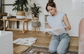 Een vrouw zit op de vloer en leest een gebruiksaanwijzing om iets in elkaar te zetten.