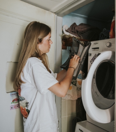 Een vrouw maakt de pluizenfilter van de wasdroger schoon