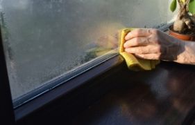 Iemand die het raam van een woning met een doekje afdoet
