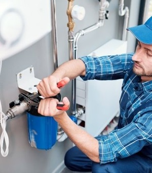 Monteur sluit een waterontharder aan op de waterleiding