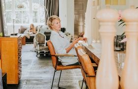 Vrouw zit aan de eettafel met een telefoon in haar hand