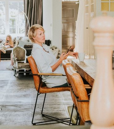 Vrouw zit aan de eettafel met een telefoon in haar hand