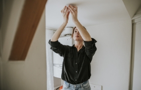 Een vrouw bevestigt een rookmelder aan het plafond