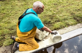 Een man zit op zijn knieën en is een dak aan het verduurzamen.