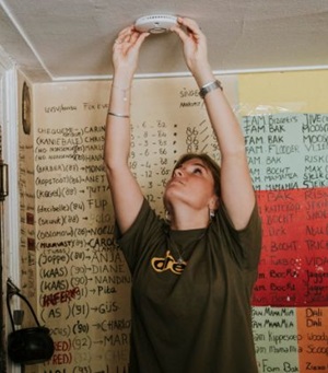 Iemand test een rookmelder die aan aan plafond hangt