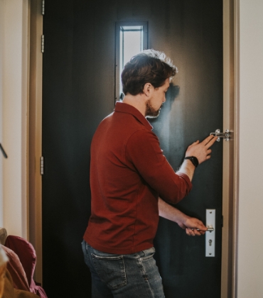 Een man doet de kierstandhouder aan de binnenkant van de voordeur.