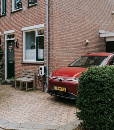 Auto op de oprit naast het huis geparkeerd, met een bankje voor het raam