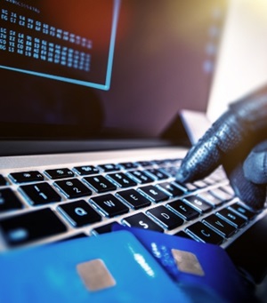 Een hand met een handschoen typt op een toetsenbord waar bankpasjes op liggen