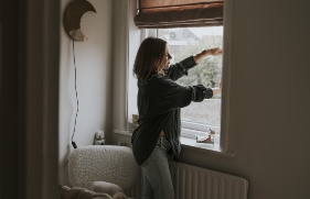 Een vrouw sluit het raam van de woonkamer om te voorkomen dat regen en wind naar binnen kunnen slaan.