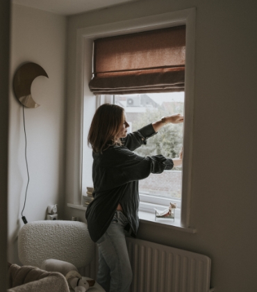 Een vrouw sluit het raam van de woonkamer om te voorkomen dat regen en wind naar binnen kunnen slaan.