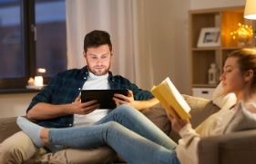 Man en een vrouw die op de bank aan het lezen zijn