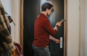 Een persoon sluit de extra deurgrendel van een voordeur, zodat deze extra beveiligd is tegen ongewenst bezoek.